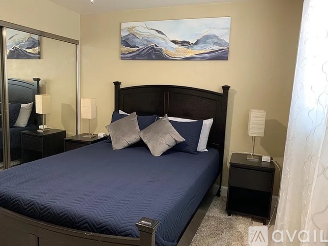 A bedroom with a large bed and a painting on the wall.