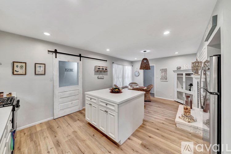 A kitchen with white cabinets and a wooden floor.