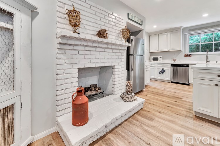 A white kitchen with a fireplace and wooden floors.