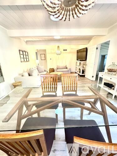 A modern dining room with a glass table and chairs.