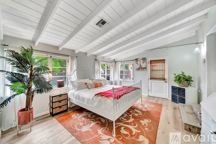 A bedroom with a white bed and a red rug.