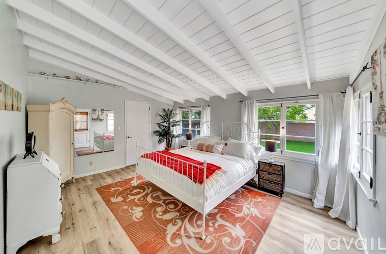 A bedroom with a white bed and a red rug.
