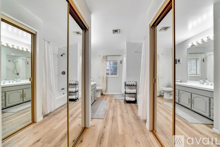A bathroom with a large mirror and wooden floors.