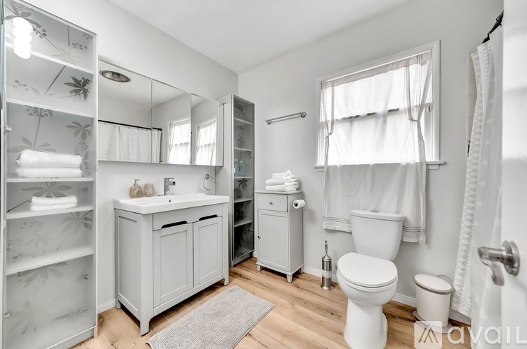 A white bathroom with a toilet, sink, and a mirror.