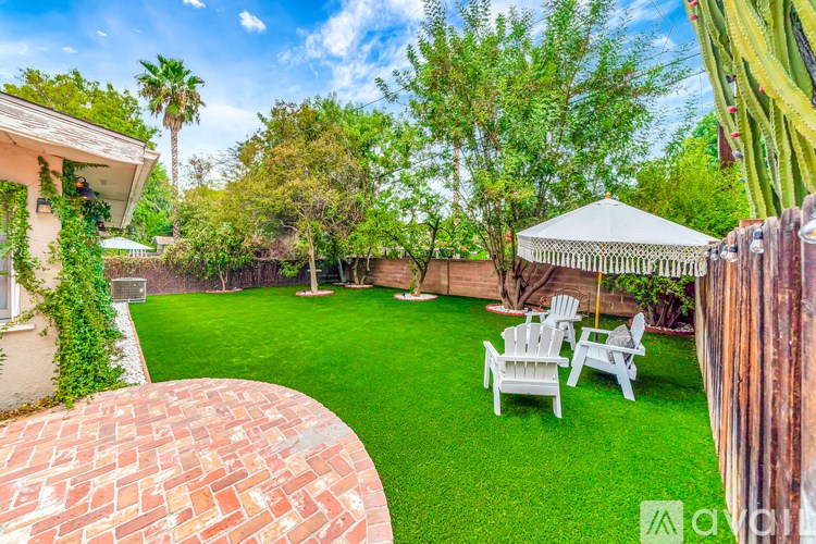 A backyard with a white gazebo and white chairs.