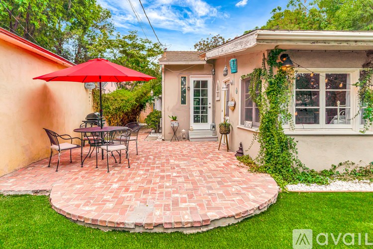 A patio with a table and chairs is surrounded by a brick border.