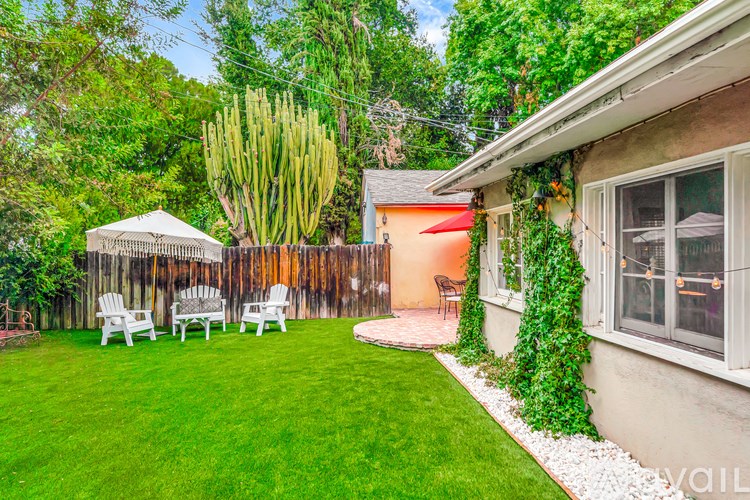 A backyard with a white umbrella and chairs.
