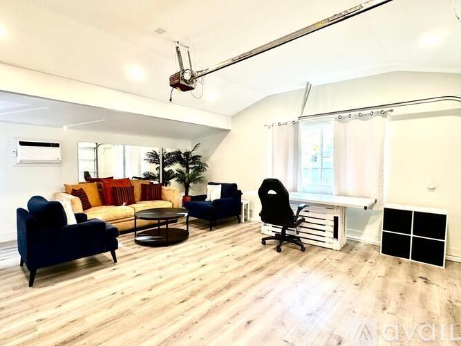 A living room with a blue couch, a black chair, and a wooden floor.