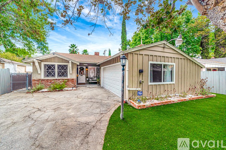 A house with a brown roof and a white fence is for sale.