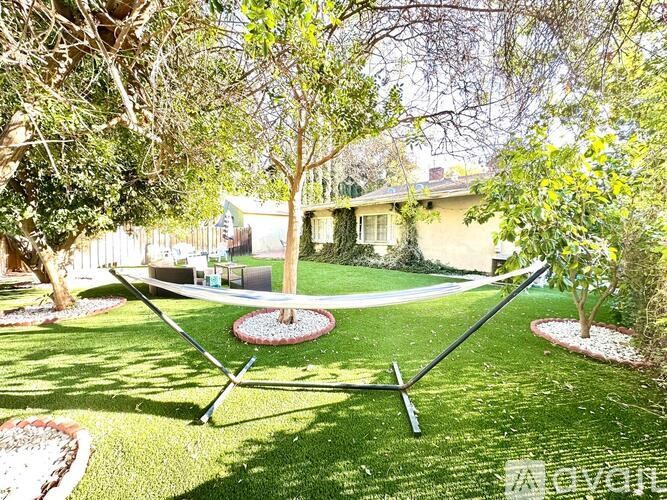 A swing set in a backyard with a house in the background.