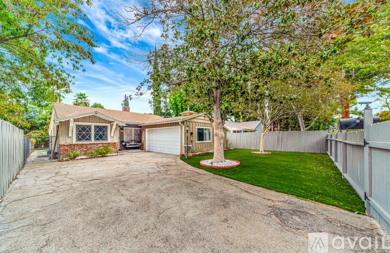 A house with a driveway and a tree in the front yard.