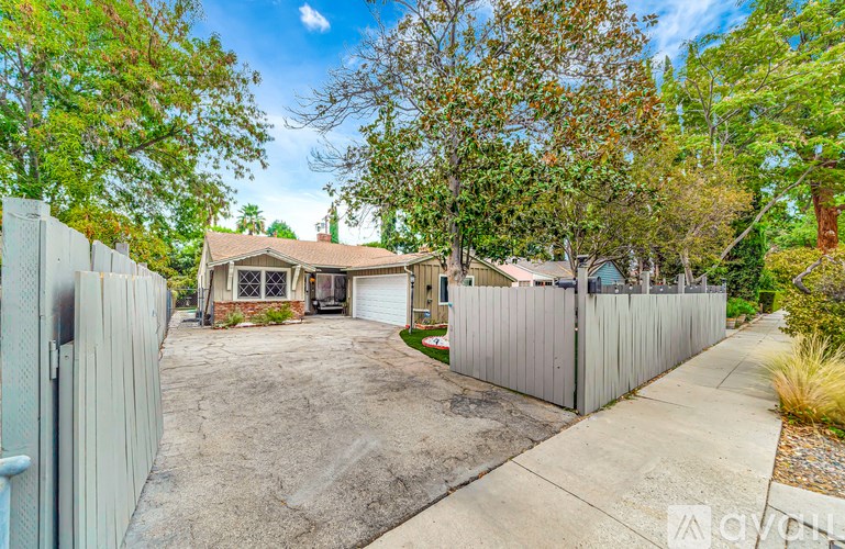 A house with a driveway and a fence in front of it.