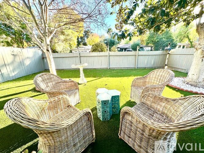Four wicker chairs are arranged in a circle on a lawn.