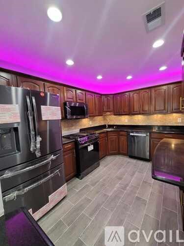 A kitchen with wooden cabinets and a black fridge.