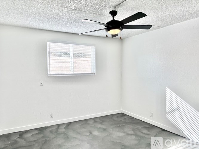 A room with a ceiling fan and a window with blinds.