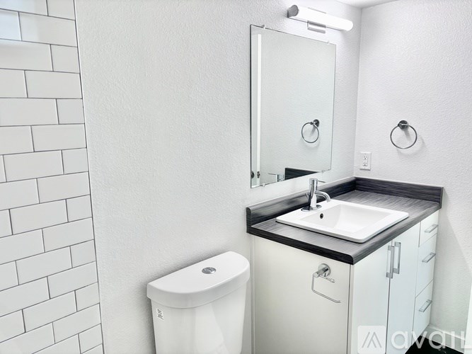 A white bathroom with a toilet, sink, and mirror.