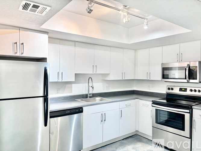 A modern kitchen with white cabinets and stainless steel appliances.