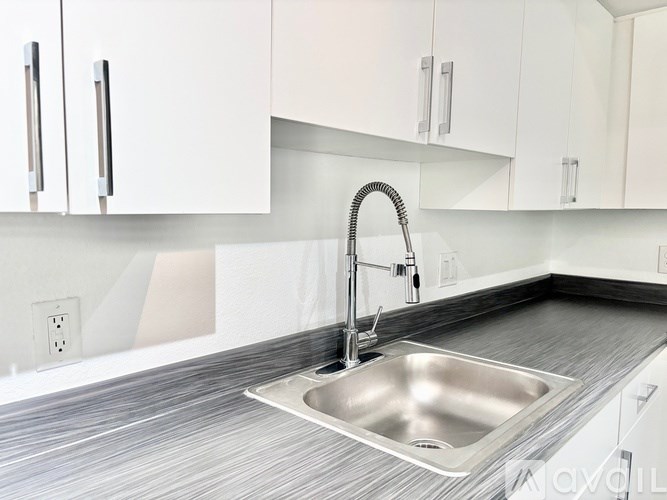 A modern kitchen with a stainless steel sink and white cabinets.