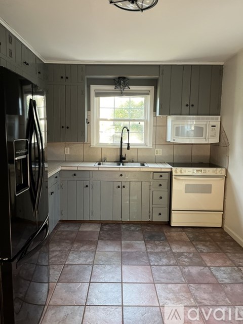 A kitchen with a black refrigerator and a white microwave oven.