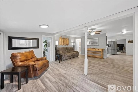 A living room with a brown leather couch and a wooden floor.