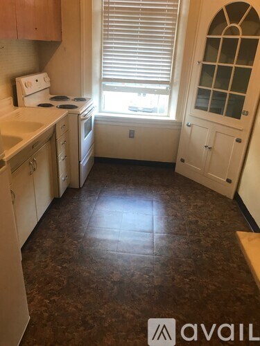 A kitchen with brown tiled floors and white appliances.