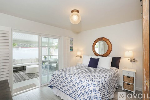 A bedroom with a bed, nightstand, and sliding glass doors.