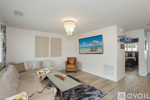 A living room with a couch, a chair, a coffee table, and a painting on the wall.
