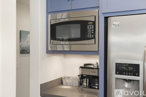 A modern kitchen with a stainless steel refrigerator and microwave.