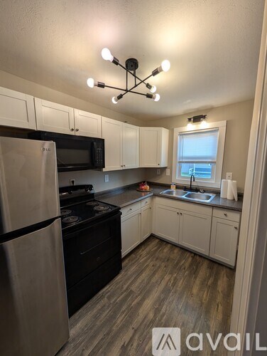 A kitchen with a refrigerator, microwave, oven, and sink.