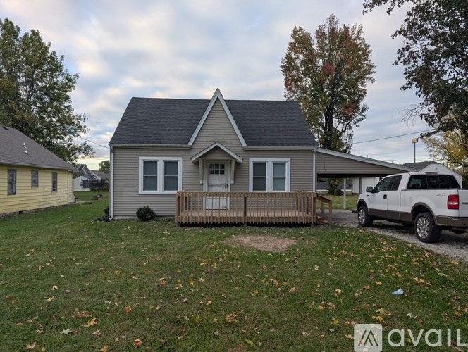 A house with a grey roof and a white picket fence is available for sale.