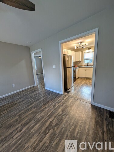 A room with wooden flooring and a doorway leading to another room.