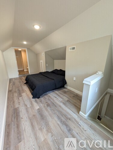 A bedroom with a bed and a wooden floor.