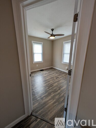 A room with a ceiling fan and two windows.