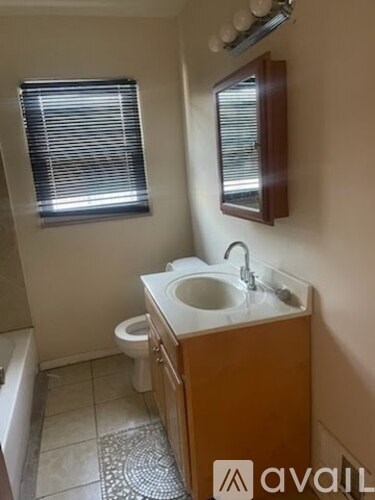 A bathroom with a toilet, sink, and mirror.