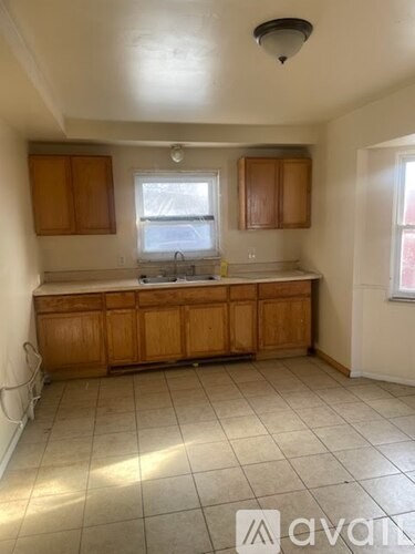 A kitchen with wooden cabinets and a tiled floor.