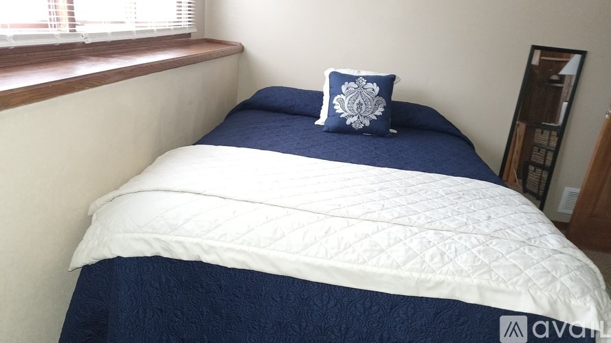 A bed with a white and blue comforter and a blue and white pillow.