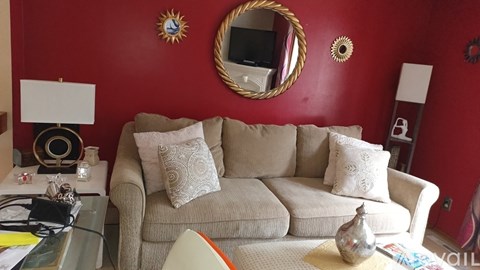 A living room with a beige couch and a round mirror on the wall.