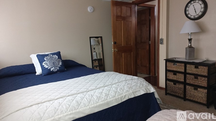 A bedroom with a bed, nightstand, and a clock on the wall.