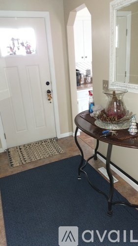 A hallway with a white door and a round table with a vase on it.
