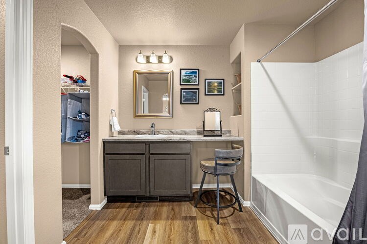 A bathroom with a sink, mirror, and a chair.