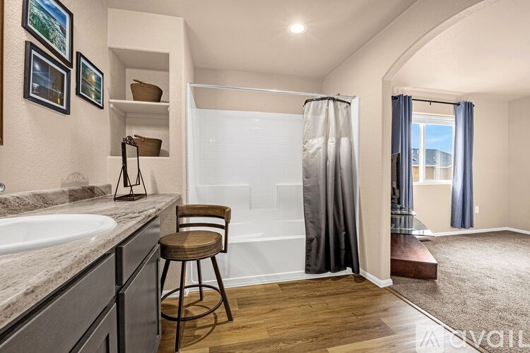 A bathroom with a white sink, a brown stool, and a shower with a curtain.