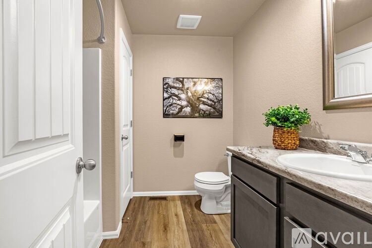 A bathroom with a toilet, sink, and a painting on the wall.