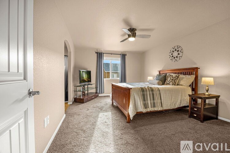 A bedroom with a bed, a ceiling fan, and a window with curtains.
