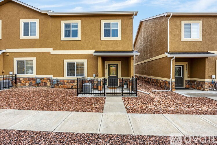 A row of houses with brown exteriors and black fences.