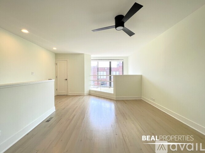 A spacious room with a ceiling fan and wooden flooring.