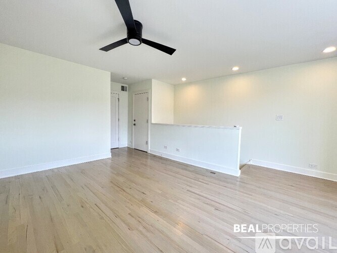 A room with a ceiling fan and wooden flooring.