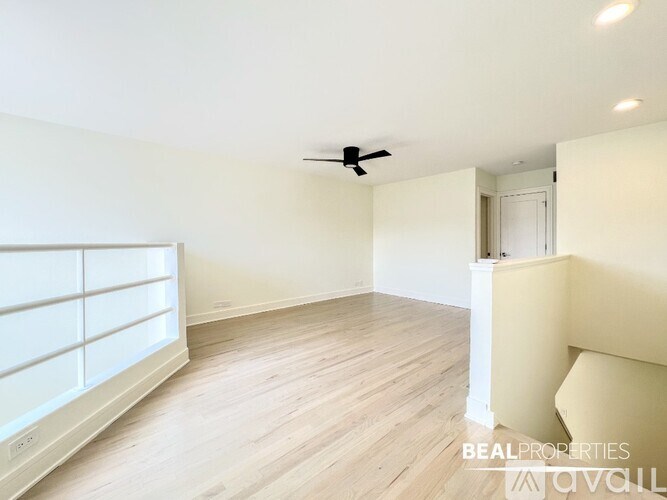 A spacious room with a ceiling fan and light wood flooring.