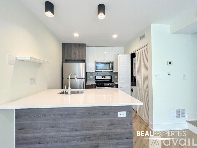 A modern kitchen with a white countertop and a stainless steel refrigerator.