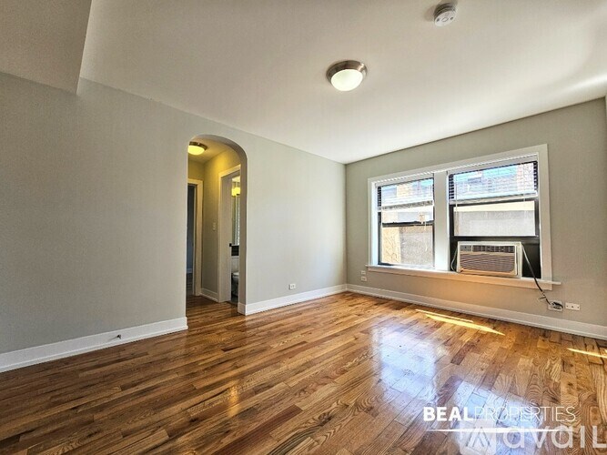 A room with wooden floors and a window with blinds.