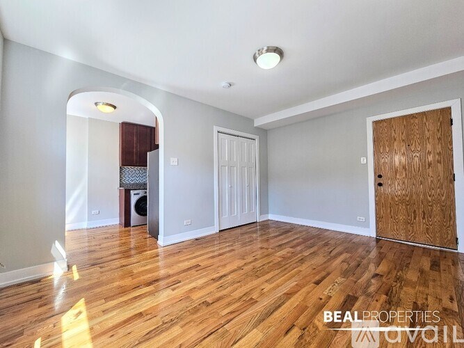 A spacious room with wooden floors and a white door.